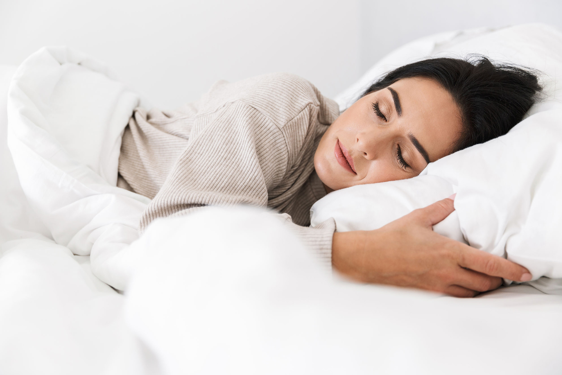 Photo of middle-aged woman 30s sleeping while lying in bed with white linen at home